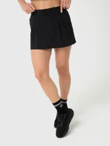 Falda deportiva tipo skort color negro, con diseño de tablas, trabillas para cinturón y bolsillos laterales. Incluye short interior con bolsillo integrado, confeccionada en tejido con tecnología Aircool de secado rápido.