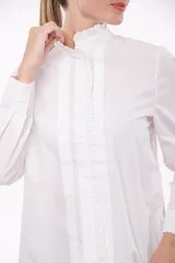 Camisa color blanco con cuello alto con volados y cierre frontal con botones ocultos.