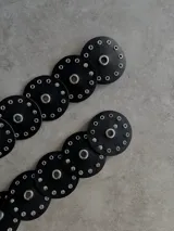 Cinturón de ecocuero negro con diseño de círculos unidos, cada uno con un ojal central grande y múltiples ojales pequeños alrededor.