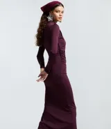 Vestido midi de manga larga en color bordó, con diseño ajustado al cuerpo, cuello redondo y detalle de pliegues asimétricos en uno de los hombros. Presenta una abertura lateral en el ruedo.
