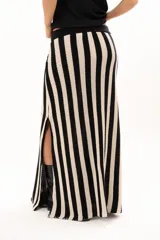 Pollera larga de tejido de punto con diseño de rayas verticales en color negro y crudo. Presenta una pretina elástica con cordón de ajuste y tajos laterales profundos que aportan movimiento.