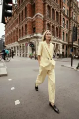 Pantalón de vestir amarillo pálido, de tiro alto, corte recto y largo a la altura del tobillo.