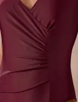 Malla enteriza de color verde militar, con diseño cruzado en V, detalle de drapeado lateral en la cintura, breteles anchos fijos y espalda pronunciada en U.