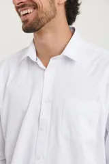 Camisa blanca de vestir, de manga larga con puños abotonados y cuello clásico.