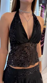 Top negro halter con escote en V pronunciado, confeccionado en tejido translúcido bordado con lentejuelas brillantes.