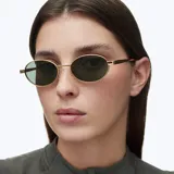 Lentes de sol con montura ovalada de acero inoxidable en color dorado y lentes polarizadas en tono verde oliva. Presentan un diseño minimalista con patillas de terminación en acetato.
