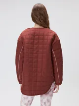 Campera reversible capitoneada con cierre frontal. Un lado es de color negro y el otro es de color beige, ambos con diseño acolchado. Cuenta con cuello redondo, mangas largas y bolsillos laterales.