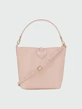 Bolso tipo bucket pequeño color rosa pálido, con asa corta y correa larga desmontable. Cierre superior con broche metálico dorado.