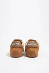 Zapatilla de perfil bajo confeccionada en serraje vacuno con estampado de manchas tipo animal print vacuno. Presenta cierre de cordones, detalle de piel en el talón con logo y suela de goma con textura de tachuelas.