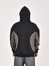 Buzo canguro negro con capucha, corte holgado y detalle de panel lateral en color verde oliva con ribete blanco. Presenta un estampado frontal con las letras "GTR".