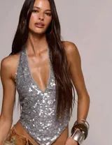 Top halter cubierto de lentejuelas plateadas, con escote en V profundo y espalda descubierta.