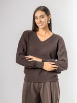 Sweater de punto color marrón con escote en V, mangas largas levemente abullonadas y diseño texturizado con patrón de escamas en la parte inferior y mangas.