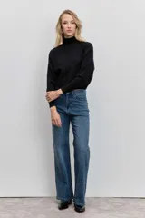 Sweater de punto color negro, con cuello alto y mangas largas de corte raglán.