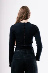 Camiseta de manga larga en color gris oscuro, con cuello redondo y costuras decorativas expuestas en el frente. Presenta un diseño ajustado al cuerpo.