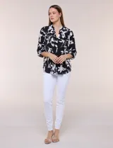 Blusa de gasa de calce suelto y caída ligera, color azul con estampado floral blanco. Presenta escote en V con cuello mao, tabla central, mangas largas regulables con presilla y botón, ruedo redondeado de estilo mullet y espalda con canesú y pliegue central.