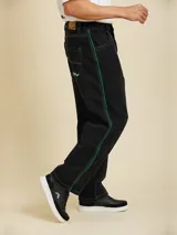 Jean de corte baggy fit, color negro, con costuras en contraste color verde y franjas laterales verdes.