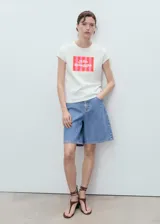 Camiseta blanca de manga corta y cuello redondo, con estampa frontal rectangular en tonos rosados con rayas verticales y la inscripción "Alla Spiaggia".