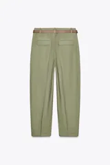 Pantalón verde oliva de lino con tiro alto, pinzas delanteras, bolsillos frontales y falsos bolsillos con solapa en la espalda. Incluye cinturón marrón y cierre delantero con cremallera, botón interior y gancho.