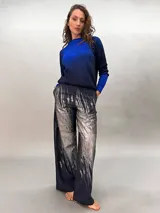 Pantalón de lana azul con estampado abstracto en tonos plateados. Tiro alto, corte amplio y bolsillos laterales ocultos.