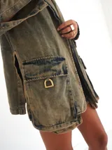 Blazer de jean 100% algodón con denim ahumado, bolsillos tipo cargo y detalles de estribos en bronce.