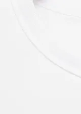 Camiseta blanca de algodón con hombreras, cuello redondo y mangas cortas estructuradas.