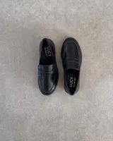 Mocasines negros con suela track y detalle de antifaz con textura croco.