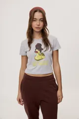Remera blanca de manga corta, con estampa frontal de un pato de hule con turbante y labios pintados, acompañada de la frase "In all else fails, denial".