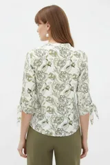 Blusa estampada de viscosa con diseño abstracto en tonos beige, negro y marrón, escote en V con cuello mao y mangas tres cuartos con detalles de lazos en los puños.