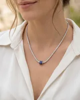 Gargantilla de plata 925 estilo tenis, compuesta por una cadena de circonias blancas brillantes y un dije central en forma de tambor con circonias azules.