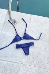 Conjunto de bikini con estampado a cuadros, compuesto por un corpiño triangular con argolla y tiras para atar al cuello y espalda, y una bombacha vedetina ancha con frunces delanteros y traseros.