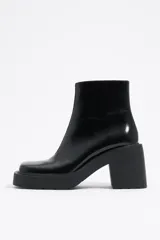 Botín de cuero negro con puntera cuadrada, cierre lateral con cremallera y tacón geométrico.