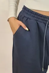 Pantalon deportivo tipo babucha de color beige, con cintura elástica ajustable mediante cordón y puños elásticos en los tobillos.