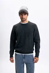 Buzo de punto de color gris oscuro, con cuello redondo y mangas largas con costuras raglán. Presenta un tejido acanalado y corte clásico.
