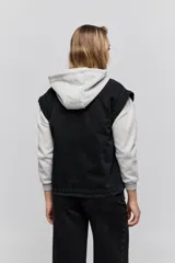 Chaleco de jean negro, de calce relajado con hombros caídos, cuello camisero, cierre frontal con botones y grandes bolsillos aplicados.