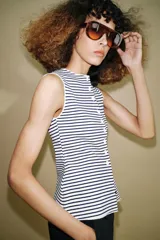 Top tipo chaleco confeccionado en hilatura con viscosa, con diseño de rayas horizontales en blanco y azul marino. Presenta cuello redondo, manga sisa y cierre frontal con botones.