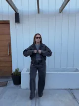 Pantalón de jean tiro medio con corte wide leg, color negro lavado, con bolsillos delanteros tipo cargo y costura vertical central en las piernas.