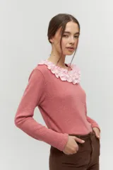 Remera de manga larga en tejido acanalado color rosa viejo, con un cuello redondo decorado con un volado amplio en color rosa claro que simula un collar.