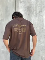 Remera marrón de corte amplio con estampado en la espalda con la palabra 'Perception' y otras frases en color dorado.