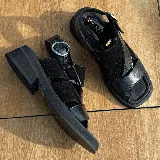 Sandalias bajas de cuero vacuno color beige, con tiras cruzadas en el empeine y ajuste con hebilla lateral.