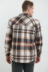 Sobrecamisa de hombre con diseño a cuadros en tonos marrón, beige y blanco. Confeccionada en tejido peludito suave, con cuello clásico, cierre frontal con botones, bolsillo superior y mangas largas con puños abotonados.
