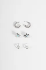 Set de tres pares de aros plateados de diferentes diseños: argollas pequeñas con textura acanalada, aros pequeños con diseño de flor con piedra celeste en el centro y aros pequeños con dije circular.