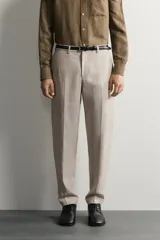 Pantalón de traje regular fit de lino color verde militar, con bolsillos laterales y bolsillos traseros de doble vivo con botón. Cierre frontal con cremallera y botón.