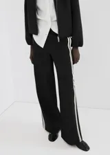 Pantalón negro de corte recto con franjas blancas laterales a lo largo de las piernas.