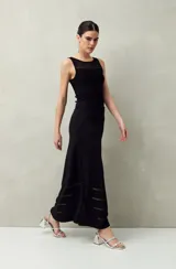 Falda larga negra de punto con silueta al cuerpo y leve evasé. Presenta transparencias lineales en el ruedo.