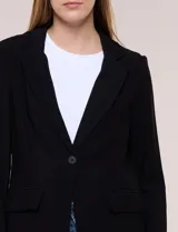 Blazer de silueta semientallada confeccionado en sastrería liviana de corte fluido, color negro, con solapa muesca clásica, cierre frontal de un solo botón, bolsillos frontales con solapa y mangas largas con puños de detalle abotonado.
