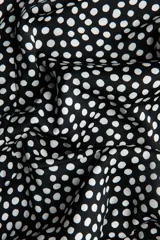 Vestido corto de escote redondo con detalle girado y abertura frontal. Presenta mangas largas amplias con aberturas en los puños, costura decorativa curva sobre la cadera y falda con leve vuelo. Incluye cierre oculto en la espalda.