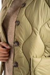 Chaleco acolchado color verde oliva, con diseño capitoneado de ondas, cierre frontal con botones y bolsillos laterales.