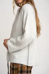 Sweater de punto en color gris melange, con diseño oversize, cuello polo y cierre frontal parcial. Presenta mangas largas y una textura acanalada suave.