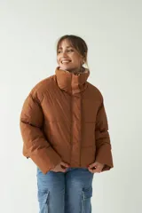 Campera puffer color marrón, corte cropped a la cadera, con cuello alto, cierre metálico y botones.