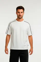 Remera de algodón de corte holgado, color blanco con detalle de líneas negras en los hombros y mangas.